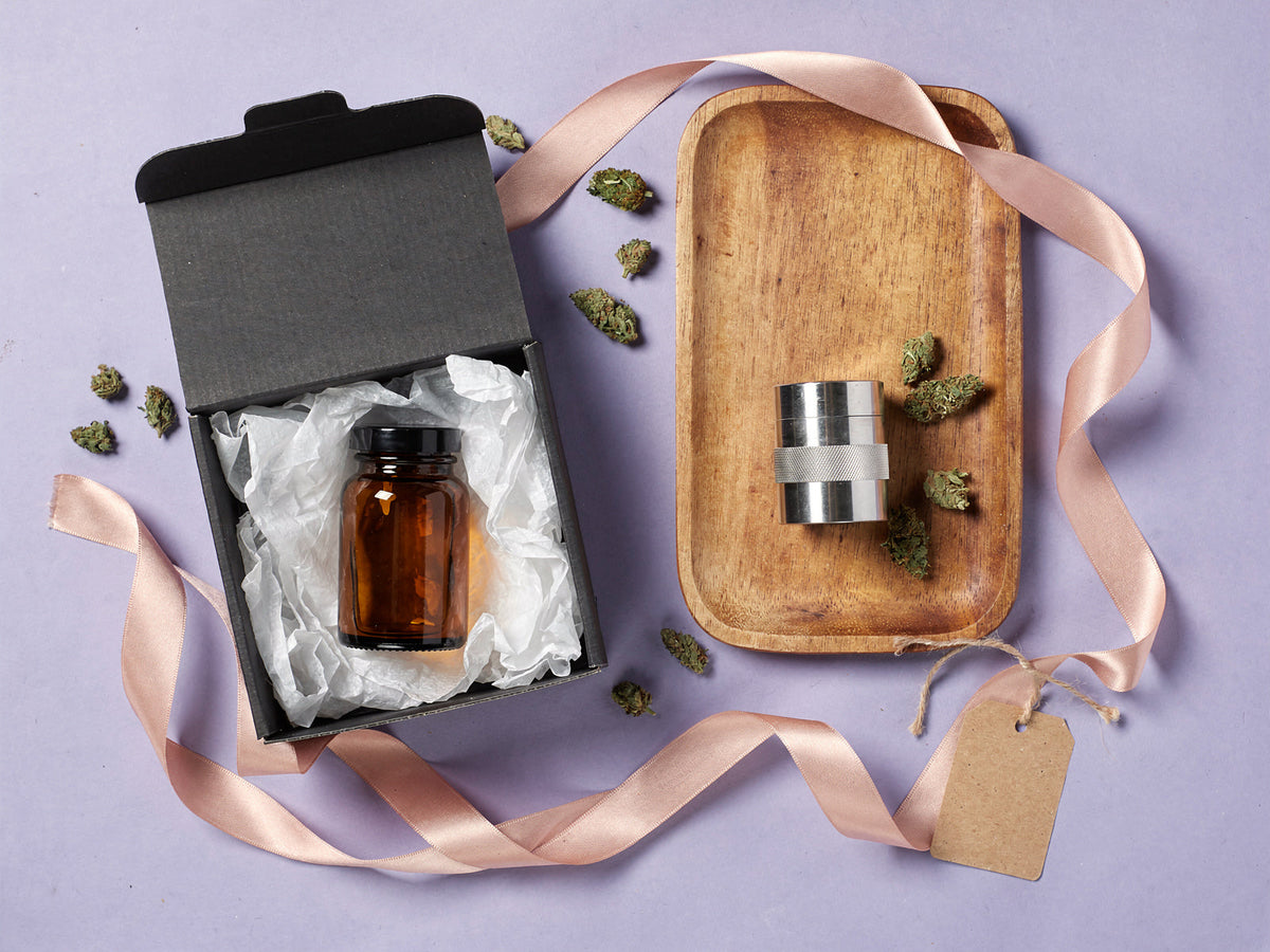 Geschenke für Kiffer: Geschenkbox mit Braunglas, Grinder auf Holztablett und Schleife